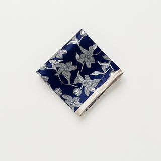 Folded women's silk bandana scarf by LuluLane with deep navy blue background featuring elegant white floral pattern and light beige border.