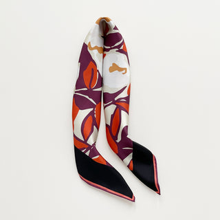 Silk bandana scarf by LuluLane with burgundy background, cream white floral print, and orangey red leaves, framed by black border with hand-rolled edges.