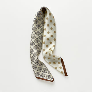 Beige silk scarf by LuluLane with intricate black paisley pattern on one side, solid cream colour on the other, featuring elegant brown border trim