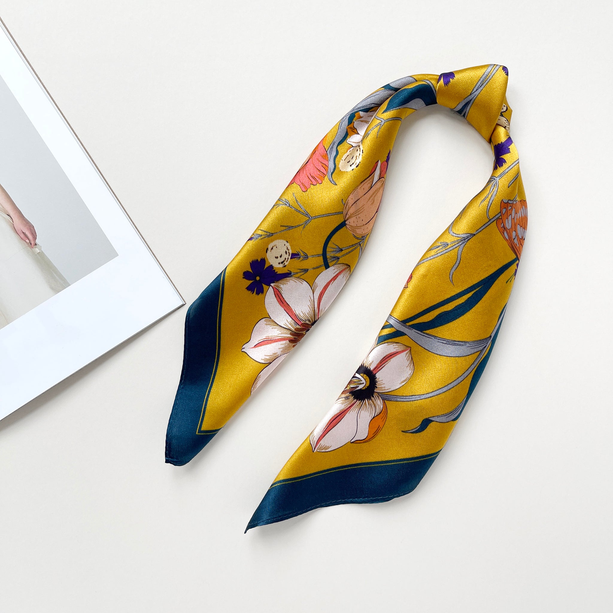 vintage vibe silk bandana scarf in vibrant mustard yellow featuring flowers and butterflies print with dark blue edge, knotted as a ponytail