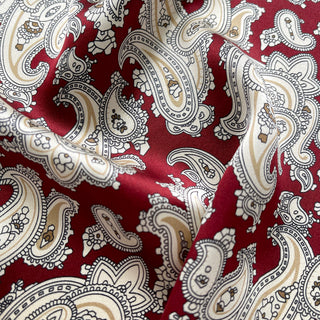 Close-up of dark red silk square neckerchief by LuluLane featuring intricate beige paisley patterns.