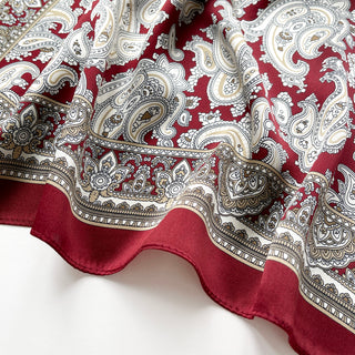 Close-up of dark red silk square neckerchief by LuluLane featuring intricate beige paisley patterns and geometric border details