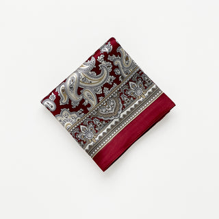 Folded dark red silk square neckerchief by LuluLane featuring intricate beige paisley patterns and geometric border details on a white background