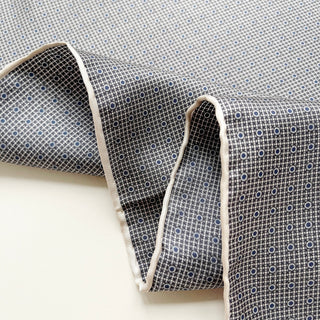 Black and white silk scarf with grid pattern and blue dots, featuring elegant hand-rolled cream edges displayed in gentle folds