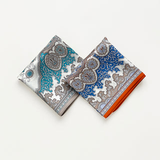 Two folded silk square scarves with baroque style pattern, featuring ornate paisley designs and intricate geometric motifs on white background