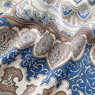 Silk scarf with intricate baroque pattern in blue, orange and beige tones, featuring ornate paisley designs and decorative orange border on luxurious fabric.