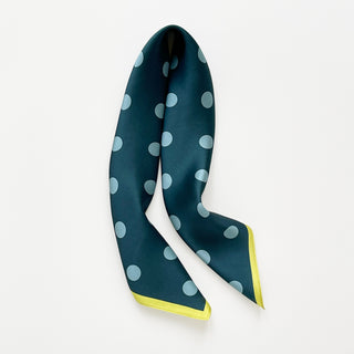 Teal green silk square scarf with light blue polka dots and a mustard yellow border, displayed draped in a triangle shape on white background