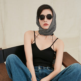 Woman wearing a black and white geometric silk scarf in 90x90cm square styled as a head scarf showcasing a modern chic look.
