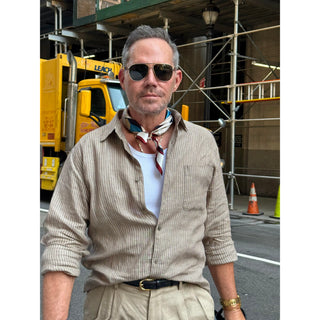 Man wearing a burgundy Bauhaus silk neckerchief with a striped linen shirt, styled as a timeless men's smart casual accessory.