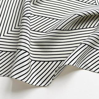 Close-up of women’s black and white geometric silk scarf in 90x90cm square design with subtle LOVE lettering and minimalist stripe pattern