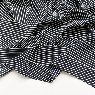 Close-up of women’s black and white geometric silk scarf in 90x90cm square design with subtle LOVE lettering and minimalist stripe pattern