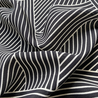Close-up of women’s black and white geometric silk scarf in 90x90cm square design with subtle LOVE lettering and minimalist stripe pattern