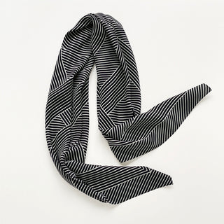 Large black and white women’s silk scarf with geometric stripe pattern and hidden LOVE motif styled in an elegant draped knot
