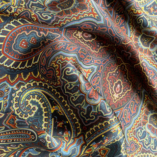 Close-up of a Navy blue silk neckerchief with intricate burgundy and gold paisley pattern in rich colour ways.