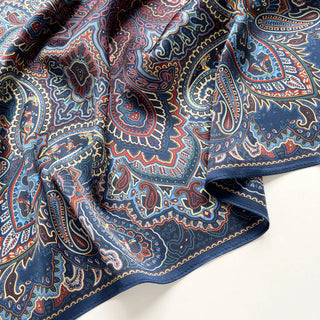 Close-up of a Navy blue silk neckerchief with intricate burgundy and gold paisley pattern, featuring rich colours and decorative border design