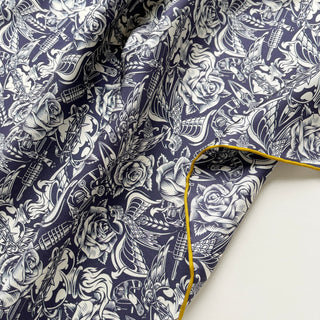 Close-up of a Retro rose silk scarf neckerchief in navy blue and ivory with vintage floral and swallow print and mustard yellow hand-rolled edges