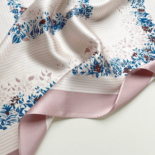 Blush pink silk scarf with elegant blue and burgundy floral leaf pattern border, showcasing lustrous fabric texture and delicate design details.