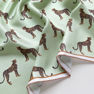 Close-up of mint green silk scarf with brown and black leopard print pattern and soft rose gold hand-rolled edges