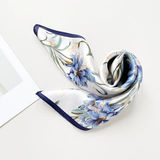 Elegant silk bandana scarf with delicate blue bell floral pattern on white background, featuring navy blue trim and soft flowing fabric