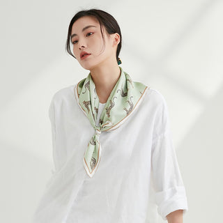 Woman wearing a mint green silk scarf with brown and black leopard print pattern and soft rose gold hand-rolled edges in white blouse