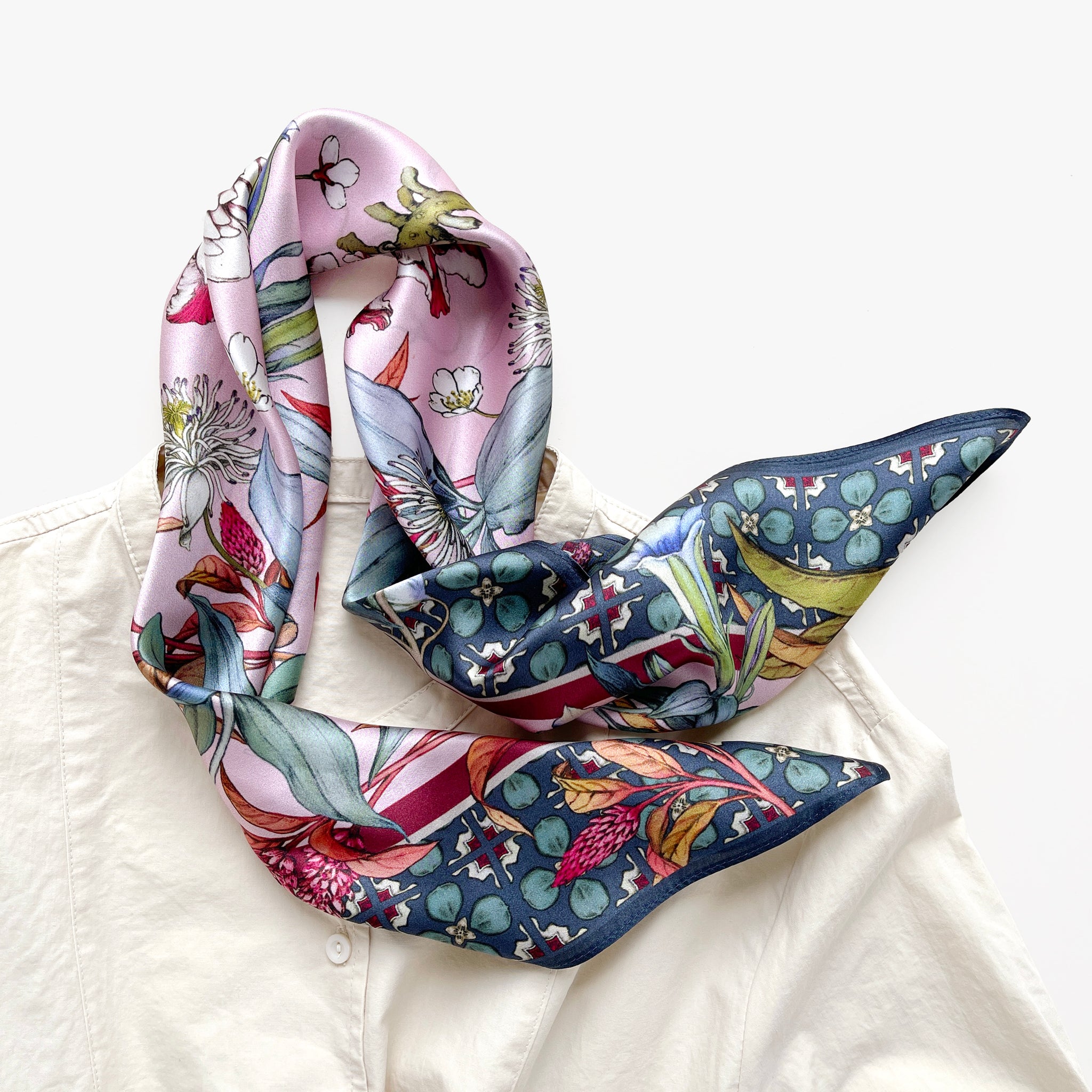 a pink base silk scarf featuring botanic floral print paired with a light beige turtle neck shirt