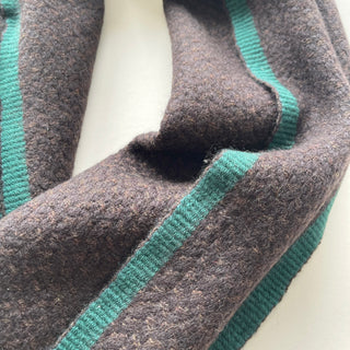 Close-up of soft dark chocolate brown cashmere with teal green knitted contrast edging.