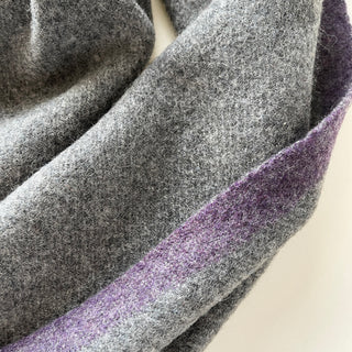 Close-up of soft heather grey cashmere with a purple contrast border.