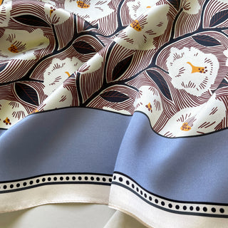 Silk lavender bandana scarf featuring white rock rose print with brown detailing, orange centers, blue border trim and dotted edge pattern.