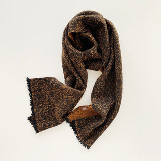 Black and warm brown unisex cashmere scarf arranged to show its compact shape and flecked texture.