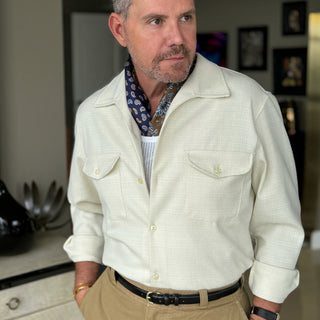 Man wearing navy floral and paisley silk neckerchief by LuluLane with cream jacket shirt and beige trousers for a sharp and crisp look.