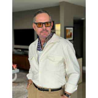 Men’s navy floral and paisley silk neckerchief by LuluLane paired with beige trousers and cream jacket shirt – refined casual look.