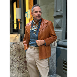 Man wearing brown leather jacket and denim shirt styled with a mustard brown and turquoise paisley silk neckerchief scarf – men’s silk scarf by LuluLane.