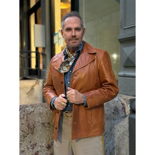 Man wearing brown leather jacket and denim shirt styled with a mustard brown and turquoise paisley silk neckerchief scarf – men’s silk scarf by LuluLane.