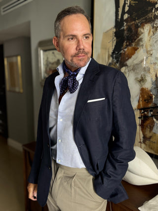 Men’s silk neckerchief in navy blue paisley on a purple base, styled with light blue shirt and navy blue suit for a smart, refined look.