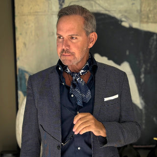 Men’s silk neckerchief styled with a blazer – Blue Kyoto floral print scarf tucked under shirt collar for a refined, layered look.