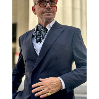 Man wearing a navy paisley patterned silk square neckerchief by LuluLane with a navy suit and sunglasses showcasing a refined sharp look.