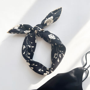 a black and white rose print silk scarf with handmade edges, knotted as a headband 