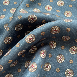 Denim blue silk neckerchief with elegant medallion pattern featuring cream circular motifs with burgundy centers and gold accents on luxurious twill fabric