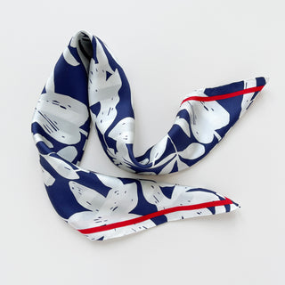 Square silk scarf with navy blue background and white floral pattern, featuring a striking red border trim, elegantly draped to showcase its luxurious texture