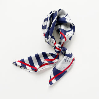 Elegantly tied navy blue and white silk scarf featuring floral patterns, bold stripes, and red border accents on a white background
