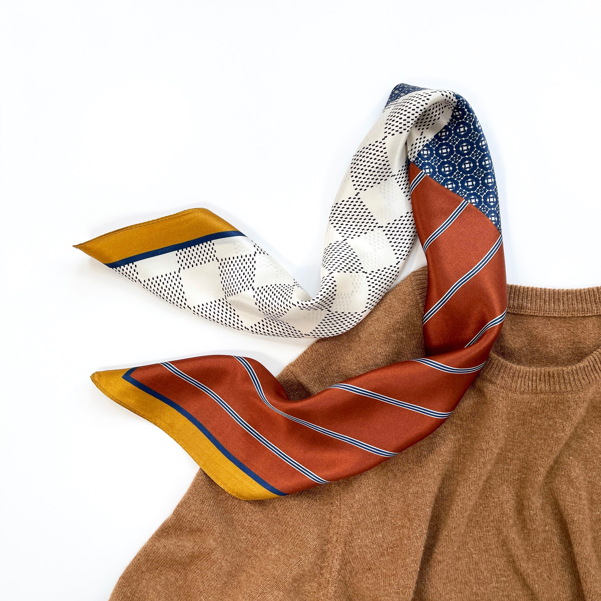 a unisex silk scarf with geometric pattern in copper, navy blue and mustard yellow