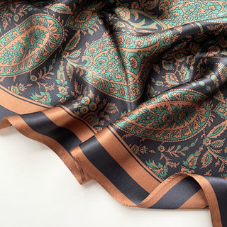 Luxurious silk scarf featuring intricate paisley pattern in black, green and copper tones with elegant border detail, displaying rich texture and sheen