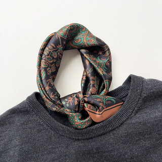 Black green silk neckerchief with intricate paisley pattern in copper and teal, elegantly styled on gray sweater collar
