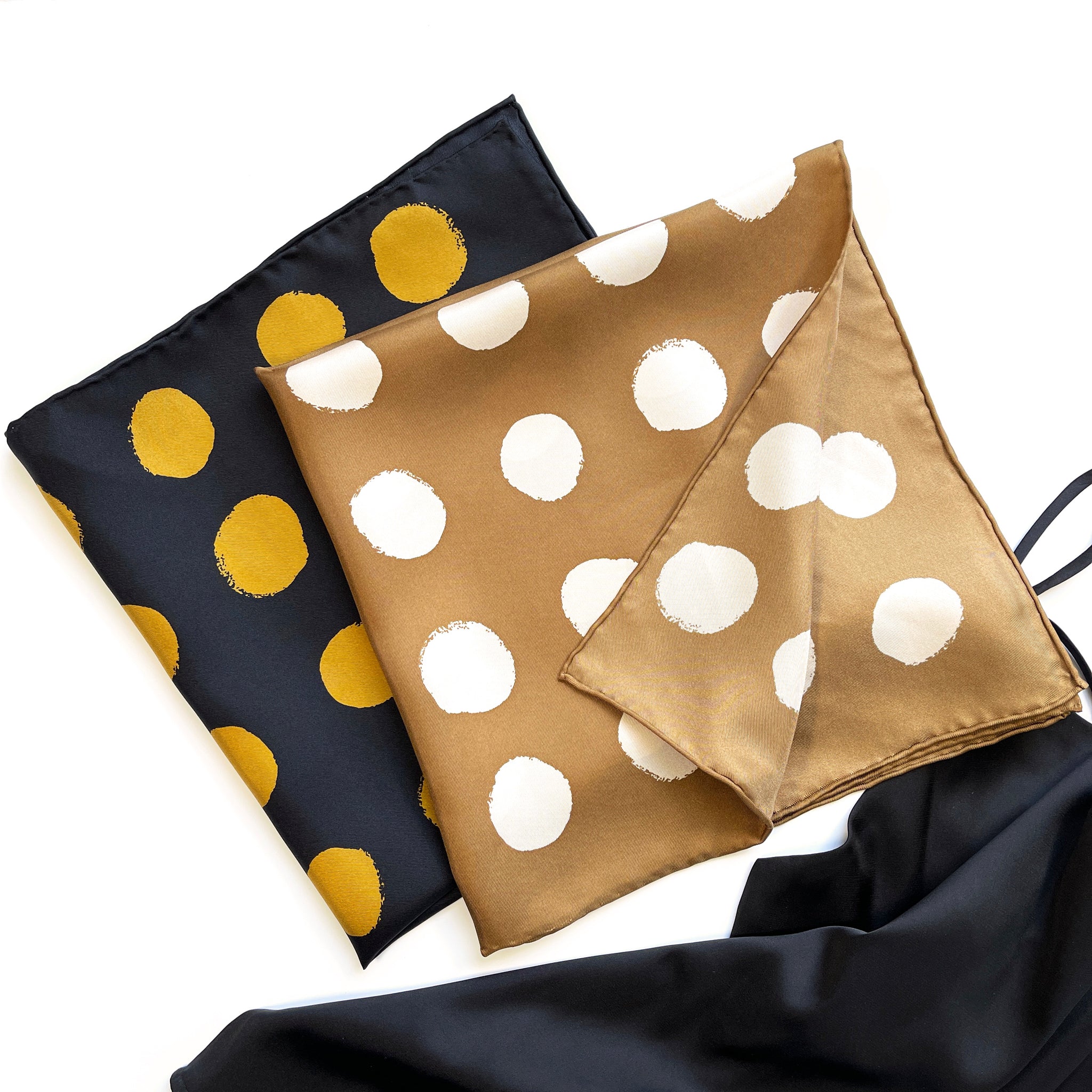 two folded polka dot print square silk scarves in classic black and beige colours with hand-rolled hems