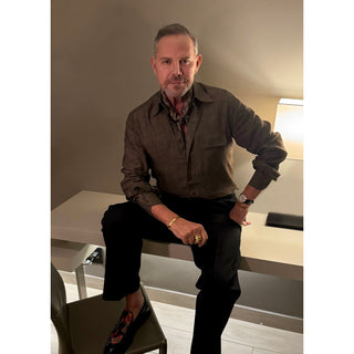 Man wearing a lead grey silk square neckerchief by LuluLane with rust red four-petal flower motif showcasing a sharp and refined look.