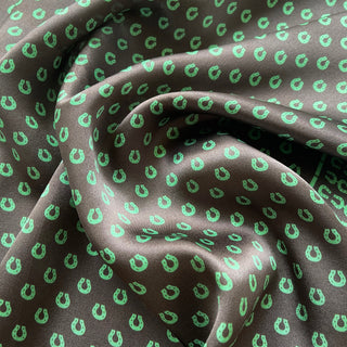 Luxurious brown silk scarf with vibrant green horseshoe pattern, showing the fabric's elegant drape and smooth satin texture