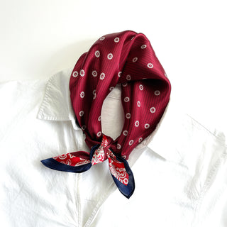 Burgundy silk bandana scarf with white floral medallion pattern, tied at neck over white shirt, featuring navy blue trim and decorative corner design