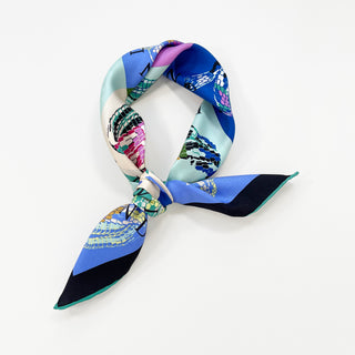 Colorful silk bandana scarf tied in knot, featuring vibrant blue, pink, green, and white color blocks with snake scale pattern design on luxurious twill fabric