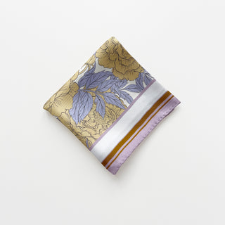 Folded silk scarf featuring light yellow peonies print on white background with lilac and ochre border, displaying hand-rolled edges
