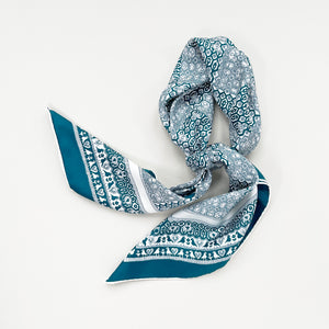 a turquoise blue square silk scarf with birds, flowers and trees prints knotted as neck scarf